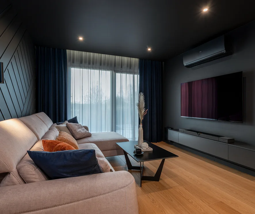 Living room with a pale sectional sofa, dark ceiling and floor-to-ceiling curtains