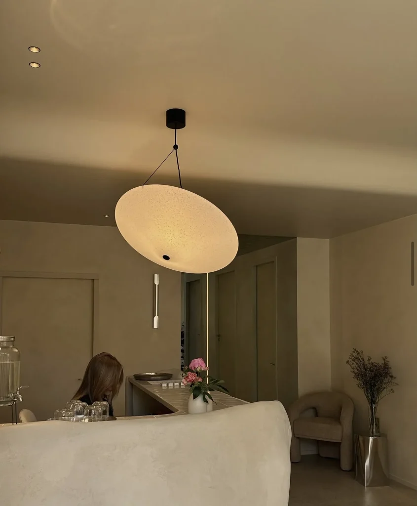The sculpted reception desk seen from the lounge, with a pendant lamp and an armchair