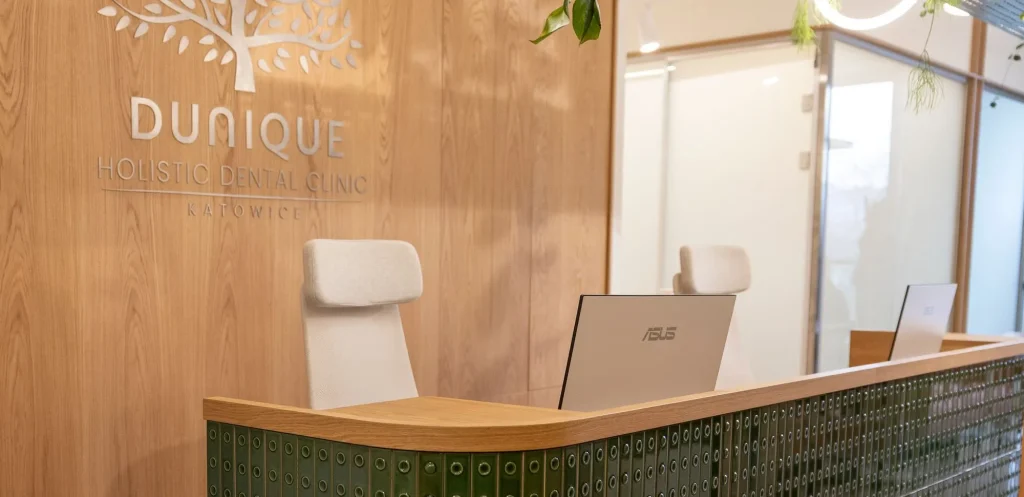 Curved reception desk clad in green artisan tiles before an oak-veneered wall with the clinic's sign