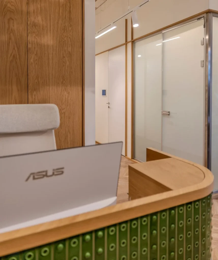 Close view of the desk's curved oak top meeting the green tile cladding