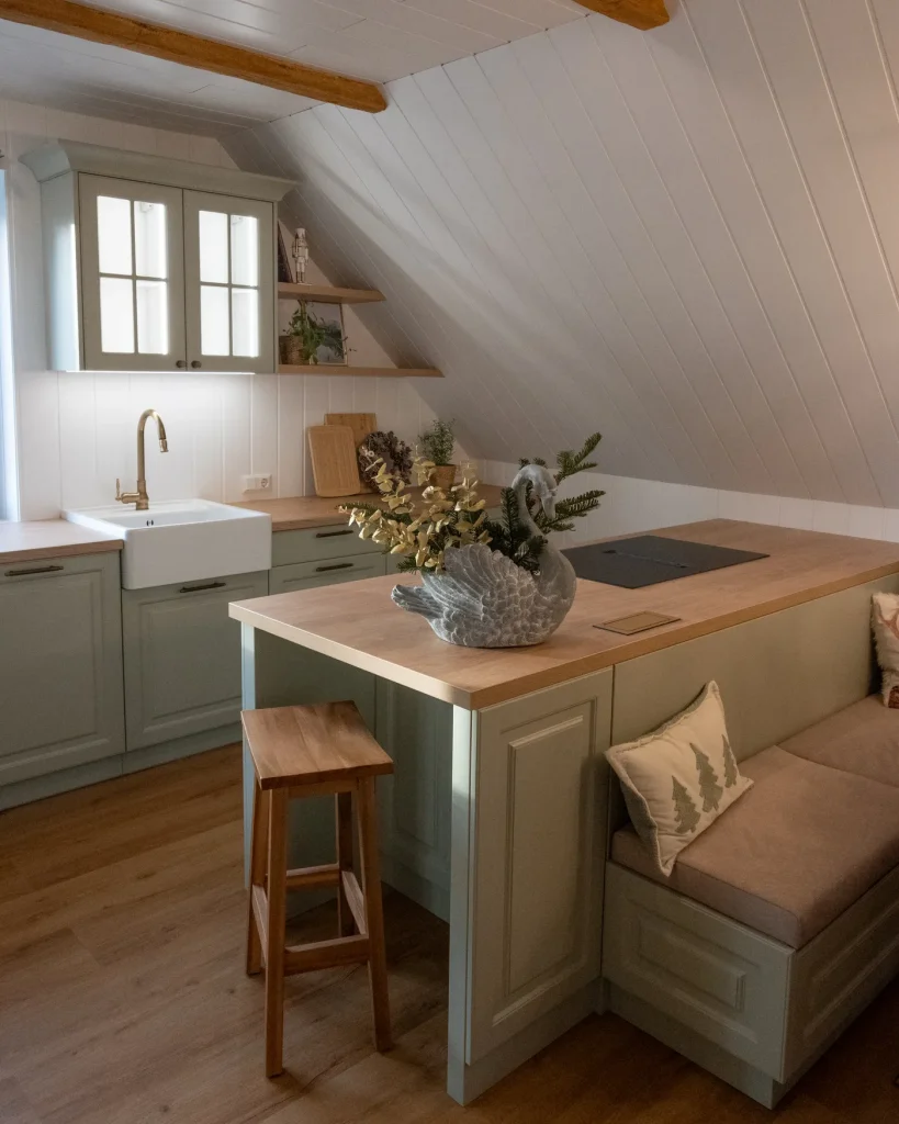 Sage lacquered shaker kitchen under a sloping timber ceiling, with a Hickory Oak island and an upholstered bench